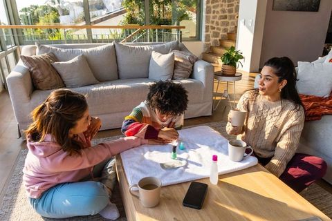 Family manicure morning painting nails with african american child in sunny living room