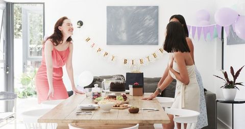 Friends preparing birthday party in bright dining room