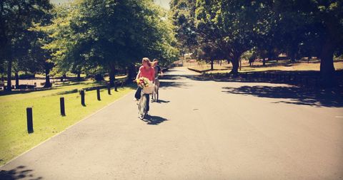 Young Woman Enjoying Leisurely Ride on Park Pathway with Flowers - Download Free Stock Images Pikwizard.com