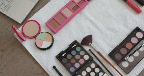 Cosmetics arrangement on towel with laptop for beauty inspiration