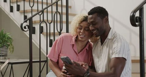 Young Diverse Friends Laughing and Chatting on Staircase with Smartphone