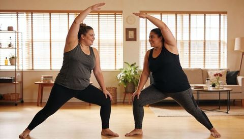 Two Women Practicing Mirroring Lunges in Bright Living Room Home Workout Together