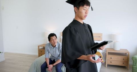 Proud Graduate Sharing Diploma with Father at Home