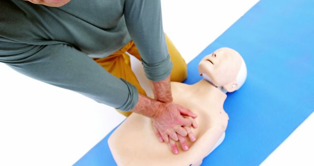  Instructor demonstrating CPR technique on dummy, emphasizing importance of hands-only CPR and emergency preparedness. Suitable for use in first aid manuals, health and safety training materials, and educational resources on emergency response.