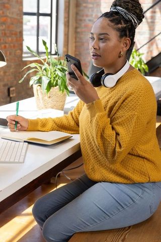 Professional woman using smartphone voice input in modern workspace