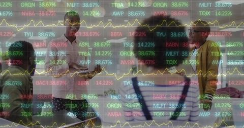Diverse businesspeople analyzing financial data overlaid with graphs