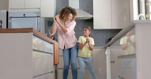 Joyful Mother and Daughter Dancing in Modern Kitchen
