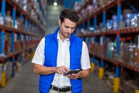 Warehouse Worker Using Tablet to Manage Inventory in Industrial Aisle