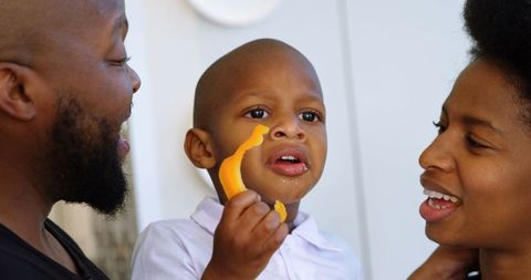 Happy Parents Watching Child Enjoy Fresh Bell Pepper at Home