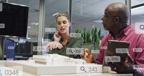 Architects collaborating over scale model with augmented data overlays in modern office