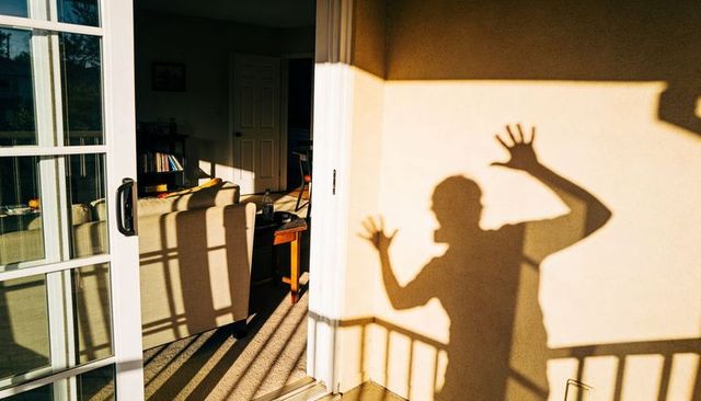 Casting shadow on balcony wall with sliding glass door and sunlit living room