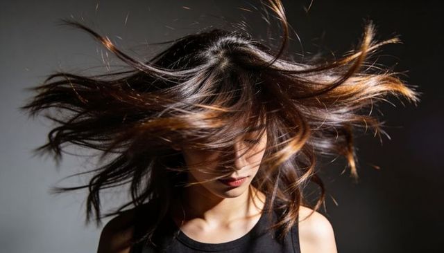 Flipping hair in motion: dramatic studio portrait with dark brown tresses and movement