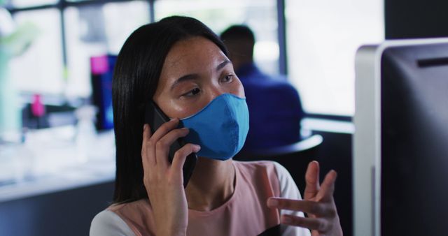 Businesswoman Wearing Facemask Having a Phone Call in Modern Office - Download Free Stock Images Pikwizard.com