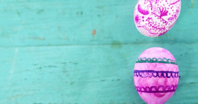 Easter eggs with intricate, vibrant hand-painted designs on rustic turquoise wooden surface. Perfect for use in holiday greeting cards, festive marketing materials, and springtime event promotions.