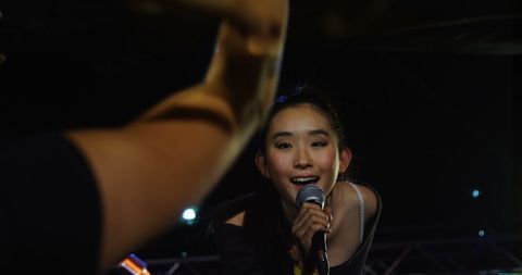 Energetic Stage Performance by Young Asian Woman Holding Microphone - Download Free Stock Images Pikwizard.com