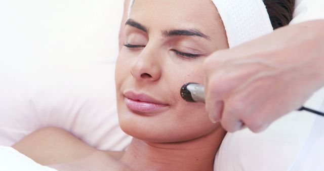 A young Caucasian woman is receiving a facial treatment from a beautician, with copy space. It captures a moment of relaxation and skincare in a spa setting.