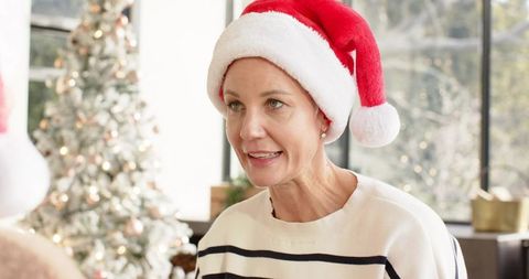 Mature women chatting in cozy holiday living room wearing santa hat by christmas tree