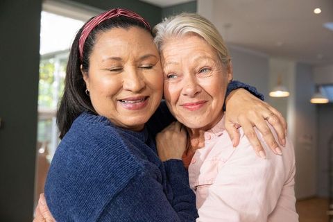 Senior women hugging in cozy home embrace, warm friendship and gentle emotional connection
