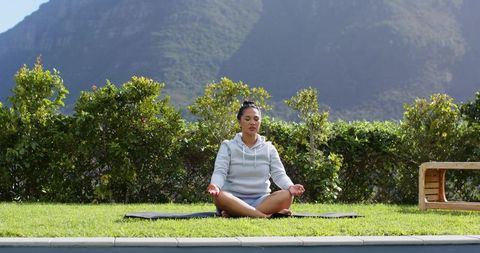 Woman Meditating Outdoors by Pool in Serene Mountain Setting