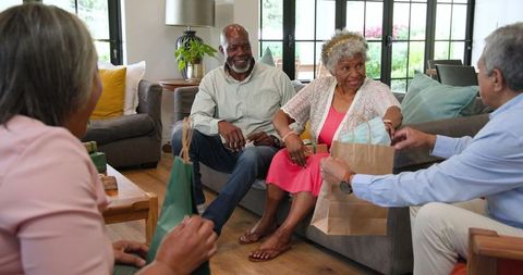 Happy Senior Friends Exchanging Gifts at Home Celebration