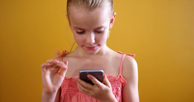 Young Schoolgirl Engaged with Smartphone Against Yellow Background - Download Free Stock Images Pikwizard.com