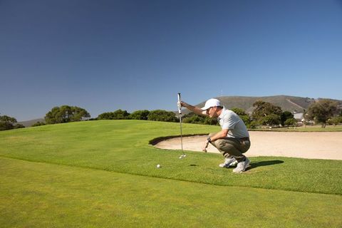 Male Golfer Assessing Putt on Lush Course Near Bunker