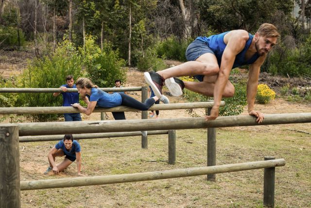 Group of people engaging in an outdoor obstacle course boot camp, showcasing teamwork, physical fitness, and endurance. Ideal for use in fitness blogs, team-building event promotions, and health and wellness articles.