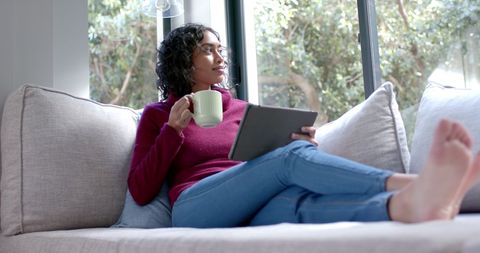 Relaxed Woman Enjoying Coffee While Browsing Tablet in Cozy Living Room - Download Free Stock Images Pikwizard.com