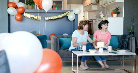 Senior friends celebrating with birthday cake in cozy living room