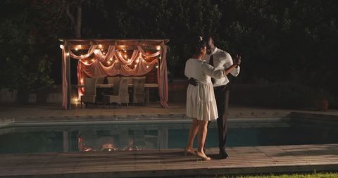 Romantic evening dance by poolside with string lights