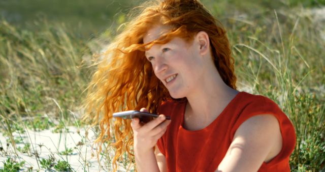 Red-haired woman using smartphone on a sunny beach - Download Free Stock Images Pikwizard.com