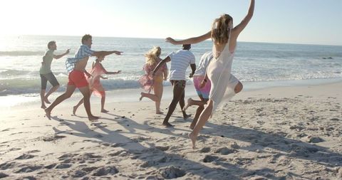 Energetic Friends Running on Sunny Beach