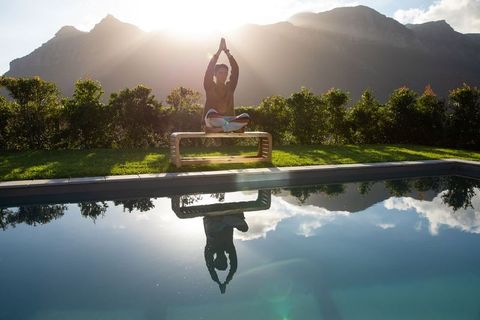 Sunrise mindfulness by pool with mountain reflection, asian man meditating serenely