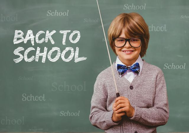 Young boy standing in front of chalkboard holding a stick, smiling. Text 'Back to School' written on chalkboard. Ideal for educational materials, school promotions, back-to-school campaigns, and classroom decorations.