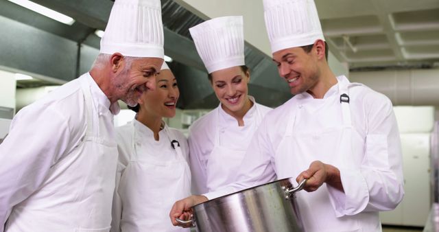 Group of chefs wearing uniforms collaborating in a professional kitchen. Perfect for articles or content on teamwork in culinary arts, professional kitchen environments, or culinary training programs. Can be used for illustrating restaurant staff dynamics or expert chef discussions.