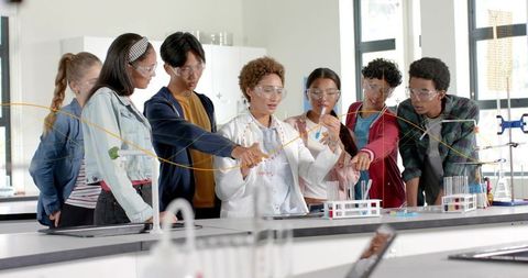 High school students collaborating on chemistry experiment in bright modern laboratory