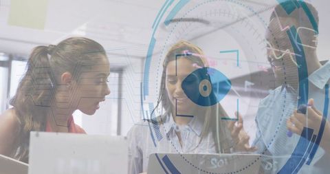 Collaborative team analyzing data on laptops with HUD overlay in modern open plan office