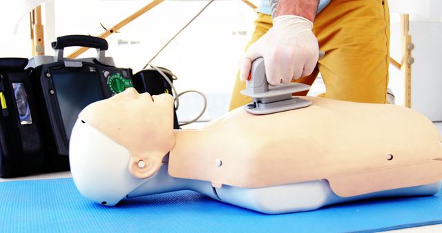A person is performing CPR on a training mannequin, simulating emergency medical procedures. This scenario is typical for first aid training courses where individuals learn lifesaving techniques.