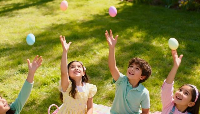 Children tossing pastel easter eggs on sunny lawn during spring picnic and outdoor play