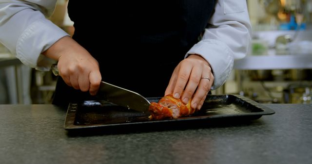 A chef is slicing a tomato on a cutting board in a professional kitchen, with copy space - Download Free Stock Photos Pikwizard.com