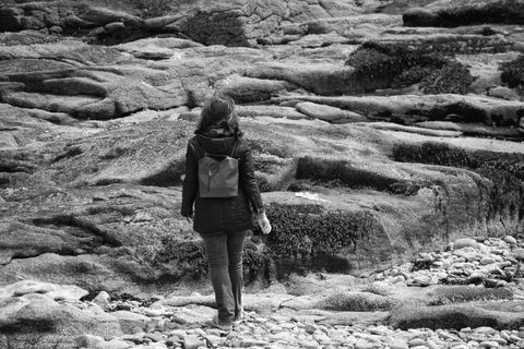 Solitary Figure Walking on Stony Coastline