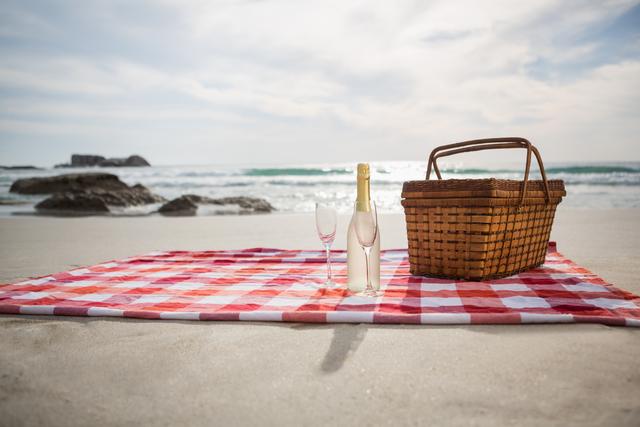 Two glasses, champagne bottle and picnic basket on beach blanket - Download Free Stock Photos Pikwizard.com
