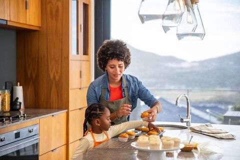 Mother and Daughter Decorating Cupcakes Sharing Moment in Sunny Kitchen