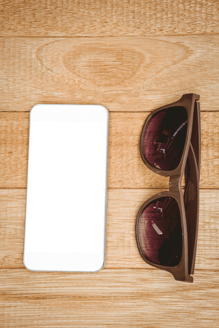 Transparent smartphone with glasses on wooden desk