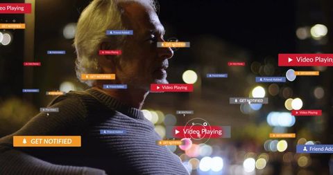 Older man leaning on rooftop railing watching floating social media notifications at night