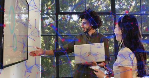 Team presenting interactive data visualization on screen with laptop and tablet in modern workspace