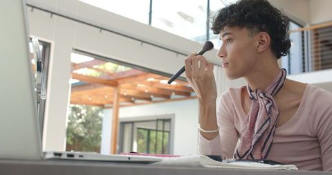 Stylish young man applying makeup at home