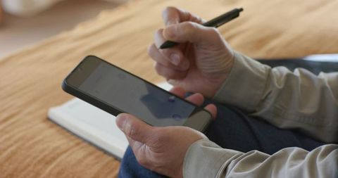 Asian adult using smartphone and stylus in cozy home environment