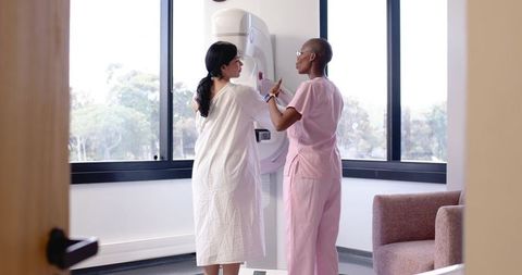 Diverse Female Patient Receiving Mammogram from Caring Nurse Technician in Bright Clinic