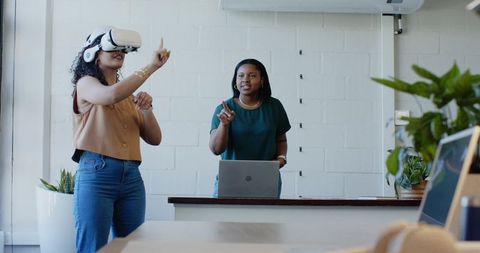 African American women testing VR headset during collaborative tech workshop in office